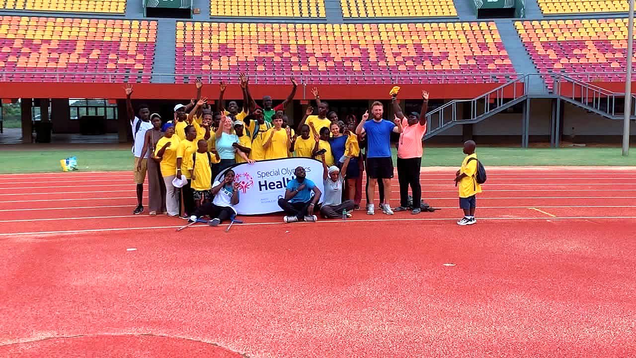 Photo de groupe des participants, bras levés, sur la piste du Stade Léopold Sédar Senghor